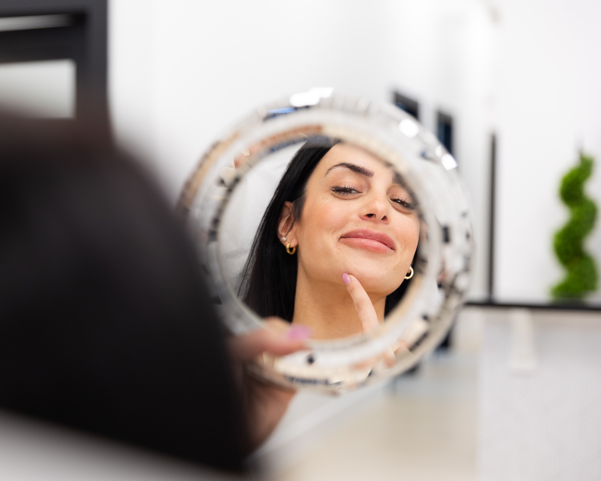 A female patient admires her reflection because she found the best sunscreen in Winter Garden at Horizons OBGYN & Aesthetics.