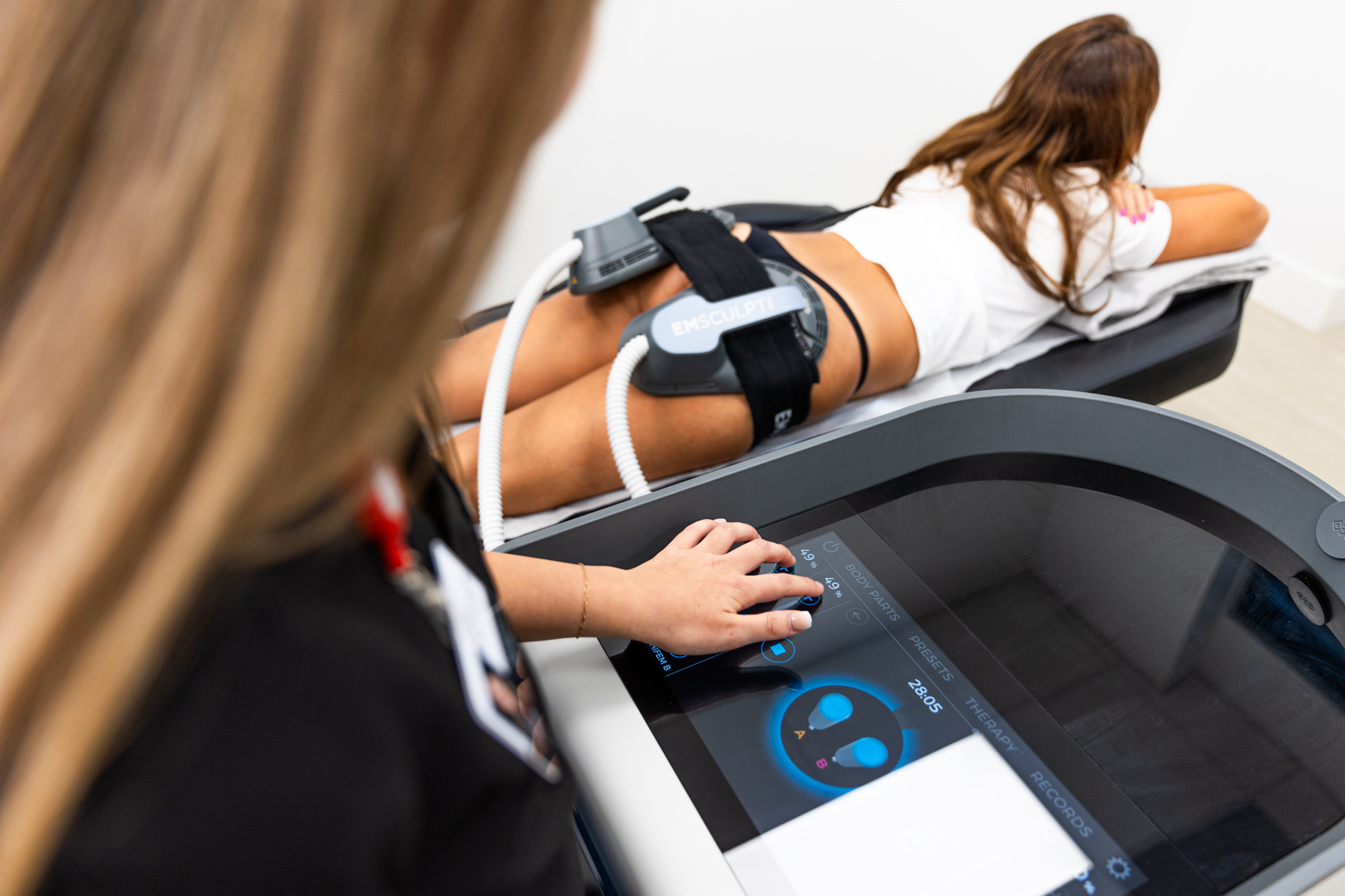 A woman lying on her stomach receiving Body Contouring in Winter Garden while a Horizons OBGYN team member runs the device