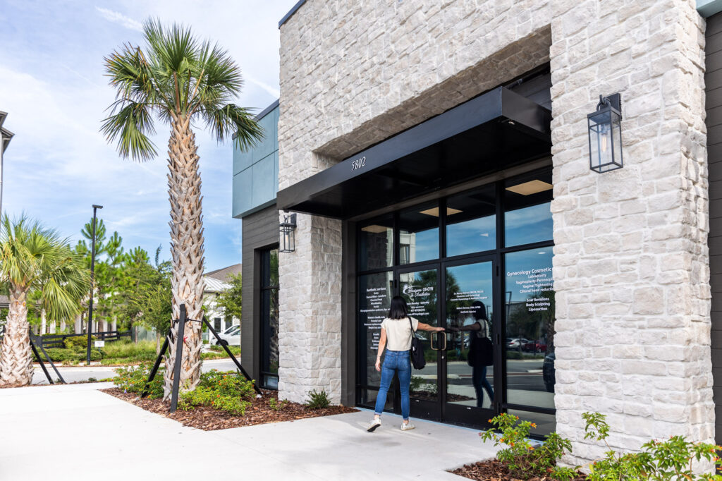 A woman opening the front door of Horizons OBGYN & Aesthetics to get TRT in Winter Garden