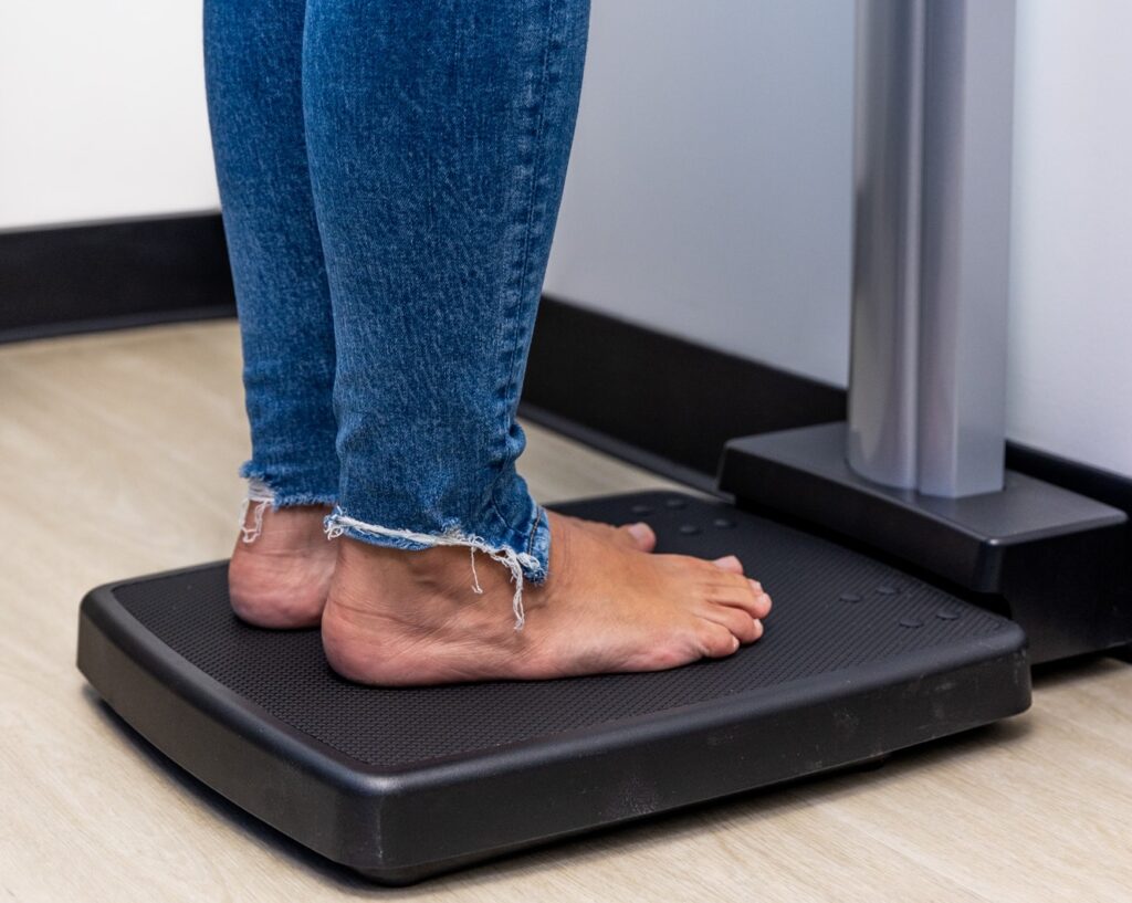 A patient's lower legs stand on a scale at our weight loss clinic in Winter Garden, preparing for our medical weight loss program.
